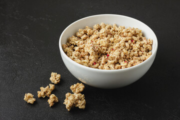 Granola in bowl on dark background.