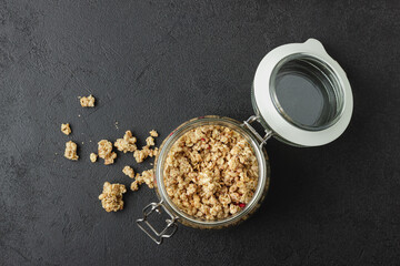 Granola in jar on dark table.