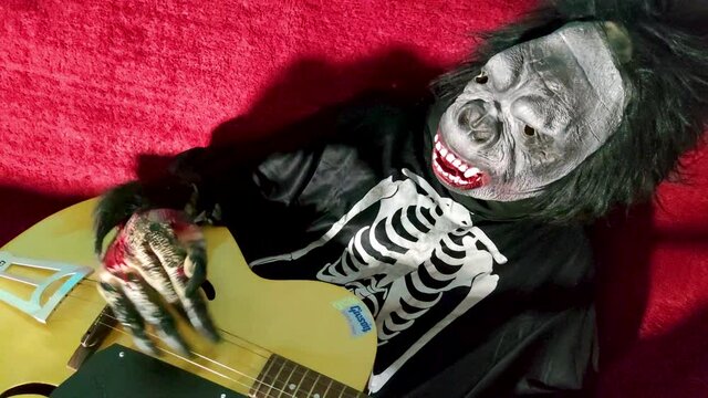 Girl in Halloween costume wearing gorilla mask playing a guitar