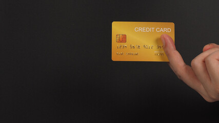 Gold color credit card in hand on black background.