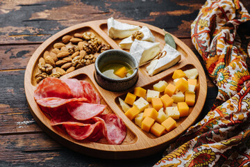 Wine snacks. Assorted cheese on a wooden board.
