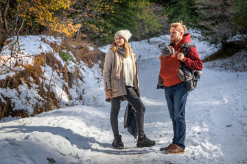 Young family with their baby boy in ergonomic baby carrier in winter nature