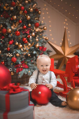 adorable baby boy  smiling and  with pine tree, star and Christmas lights on the background