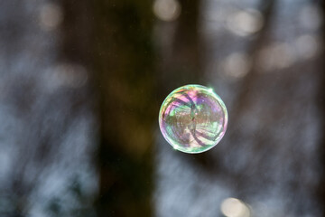 Farbenspiel fliegender Seifenblasen über Schnee und bei Sonnenschein