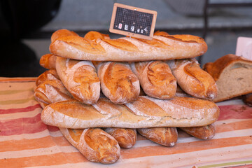 Side view on a row of fresh baguettes on a table cloth in a market