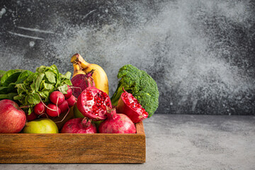 Selection of fresh fruit, greens, vegetables in wooden tray on grey stone background table, detox,...