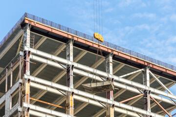 Container with concrete mortar. Crane lifts the tank with concrete mortar on the background of high-rise building under construction. Construction of buildings and constructions