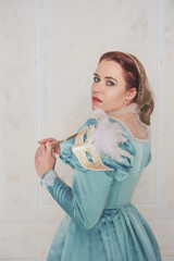Beautiful young woman in medieval style dress with mask