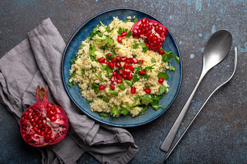 Bright colourful couscous or bulgur salad with pomegranate seeds Tabbouleh in rustic blue ceramic...