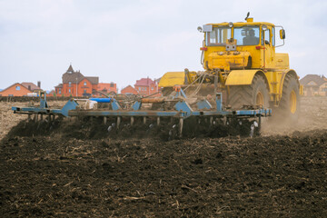 Tractor pulls disc harrow. Soil cultivation. Agricultural machine is working in the suburban field. Agrotechnical event that provides crumbling, loosening and partial mixing of the soil.
