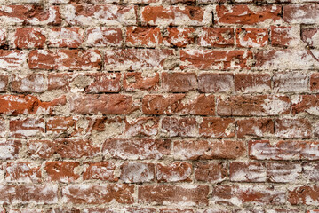 Old brick wall background with stains texture of white plaster. Closeup.