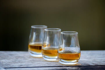 Tasting glasses of scotch whisky strong drink on old outdoor wooden table