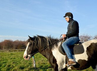 A man sits astride a piebald horse