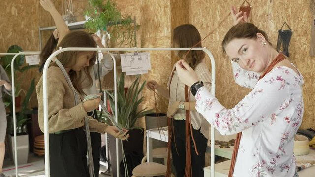 Group of women attending art class.  Female students and teacher makes home decor in Boho style in workshop together. Weaves handmade macrame at art school studio. Creativity, people education concept