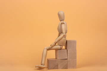 Success concept. Wooden mannequin on a ladder made of wooden blocks.