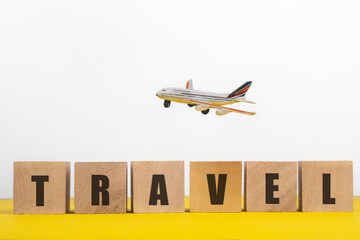 Travel concept. Wooden cubes with the inscription Travel and the plane in the background.