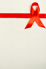 Medical concept for World AIDS Day in December. Red AIDS awareness ribbon on white background. Vertical photo. Close up