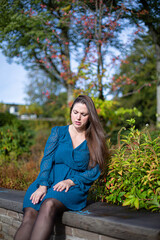 Sitting white young european woman in autumn park dressed in bright blue feel pain