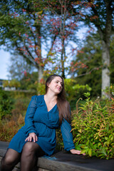 Obraz premium Smiling white young european woman in autumn park in bright blue dress
