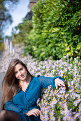 White young european woman near flowers in bright blue dress