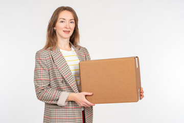 woman holds box in front of her. Portrait of girl with cardboard box. Businesswoman with parcel. Woman smiles and looks into camera. Entrepreneur has cardboard box. Businesswoman on light background