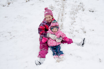 Cute happy girl rides down the slide in the snow.