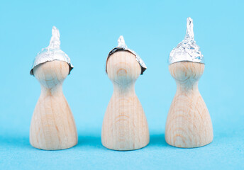 Three wooden figures wearing an alu hat, conspiracy theories, tin foil, symbolic