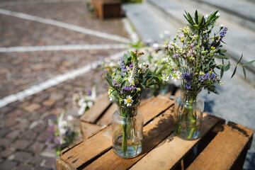 Creative beautiful wild spring daisy bouquet in glass jar stand on wooden cage box for outdoors decoration