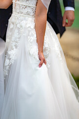 Close up view bride in white dress pose holding hand on fabric at weddings outdoors