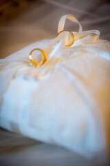 Fototapeta na wymiar Bride and groom round golden wedding rings on white cushion