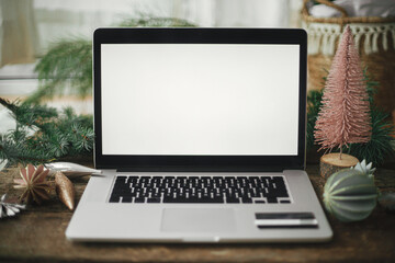 Laptop with blank screen and credit card on rustic wooden table with stylish christmas ornaments and pine tree. Christmas Sales and shopping online. Black friday and cyber monday. Space for text