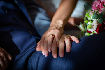 Obraz na płótnie Canvas Bride and groom sit together with hands on top each other showing wedding rings