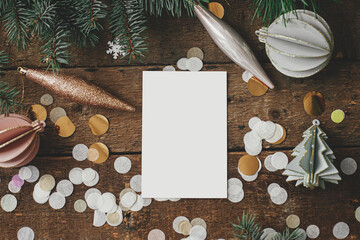 Empty greeting card and christmas ornaments, decorations, confetti and pine branches on rustic wooden background. Christmas card mock up flat lay. Space for text. Seasons greetings. Template