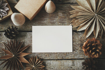 Empty greeting card and christmas paper stars, wooden tree and pine cones on rustic background....