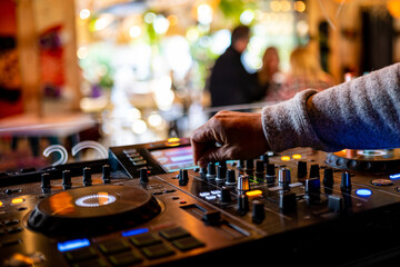 dj hand manipulating the controls of a mixing console in nightclub