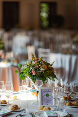 Decorated wedding tables with flowers and glassware set up in bright wedding venue for celebration - 468246460