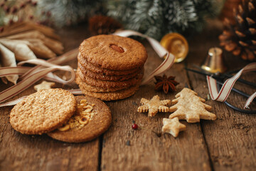 Obraz na płótnie Canvas Christmas oatmeal cookies and festive decorations on rustic wooden table. Atmospheric christmas moody image. Xmas healthy cookies and ornaments. Happy Holidays and Merry Christmas