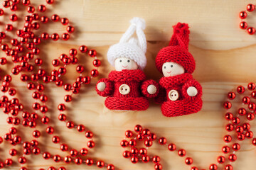 wooden toy men in knitted red sweaters on a wooden background with red beads. Christmas decor