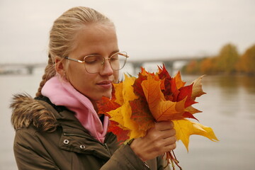 Girl holding colorful autumn leaves in her hands