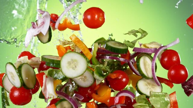 Super slow motion of fresh salad with water splashes flying in the air. Filmed on high speed cinema camera, 1000 fps.