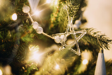 Modern glass christmas ornaments, white baubles and golden christmas lights bokeh close up. Space...