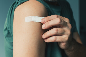 Male patient with plaster after Covid-19 vaccination and immunization procedure in hospital