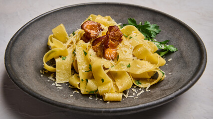 Macro panoramic pasta pappardelle with mushrooms chanterelles, cheese and parsley on black plate 