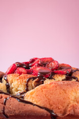 Cake with chocolate and some strawberry slices on a pink background
