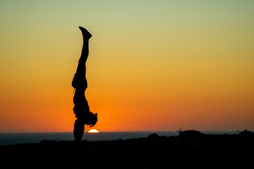 silhouette of a person in the sunset doing a handplant