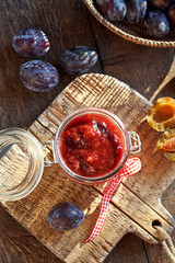 Homemade plum jam with fresh plums on a table
