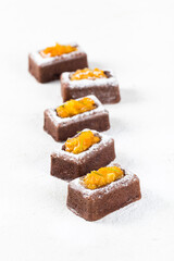 Chocolate savarin cake with tangerine filling, sprinkled with powdered sugar on a white background
