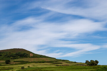 Green grassy slope with blue sky and some clouds