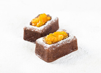 French dessert, chocolate savarin cake with tangerine filling, sprinkled with powdered sugar on a white background
