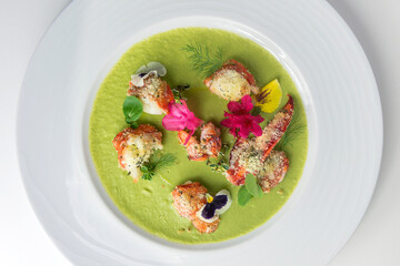 Plate with lobster on pea cream and flower petals and herb
